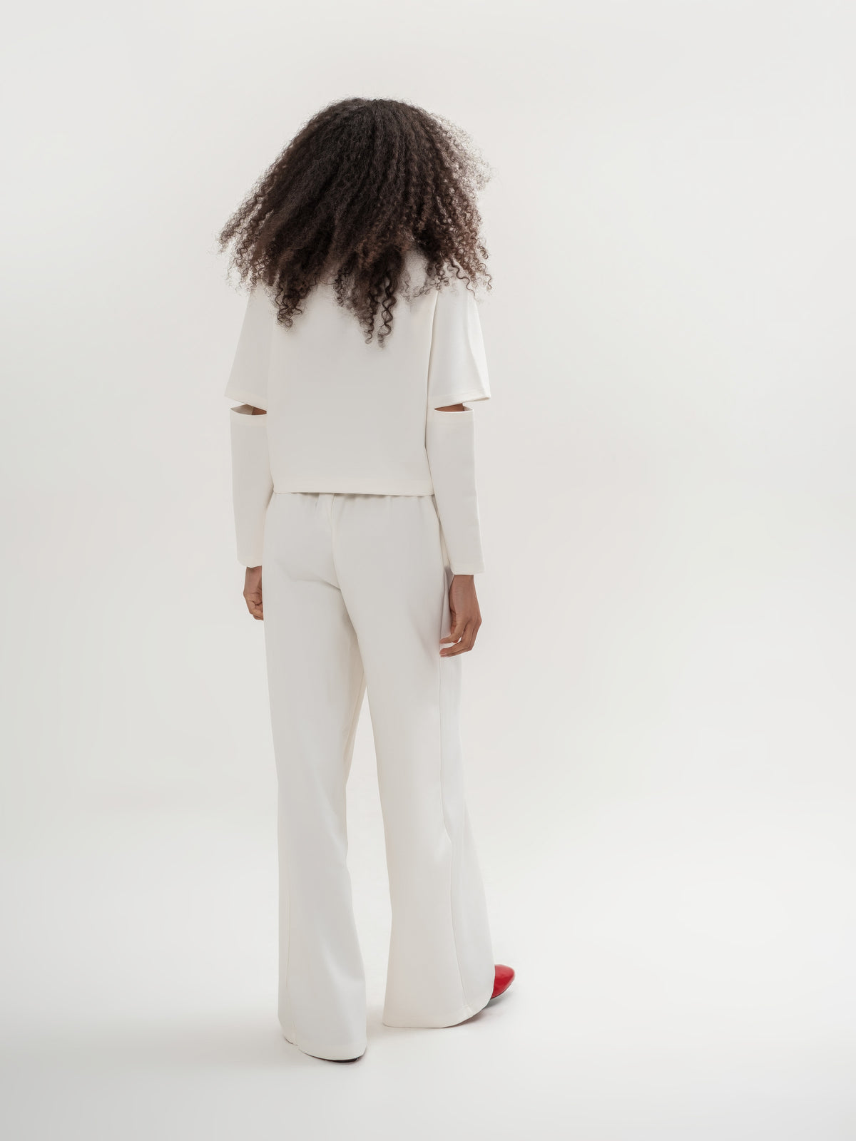 White top with slits in the elbow area and white wide leg trousers